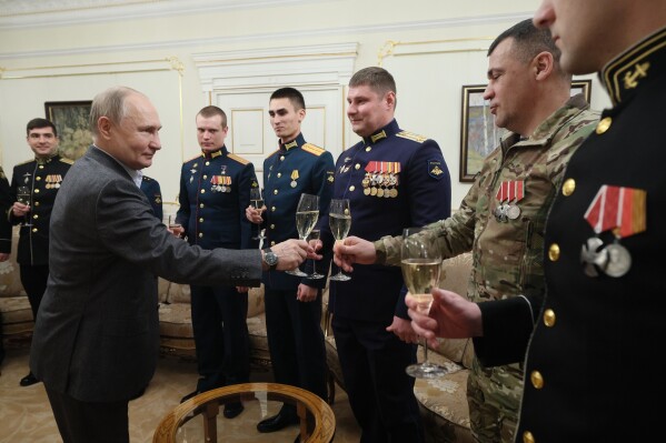 FILE - Russian President Vladimir Putin, left, shares a toast with Russian servicemen during a meeting at the Novo-Ogaryovo State residence outside Moscow, Russia, on Monday, Jan. 1, 2024. As Vladimir Putin heads for another six-year term as Russia’s president, there’s little electoral drama in the race. What he does after he crosses the finish line, however, is what’s drawing attention and, for many observers, provoking anxiety. (Gavriil Grigorov, Sputnik, Kremlin Pool Photo via AP, File)