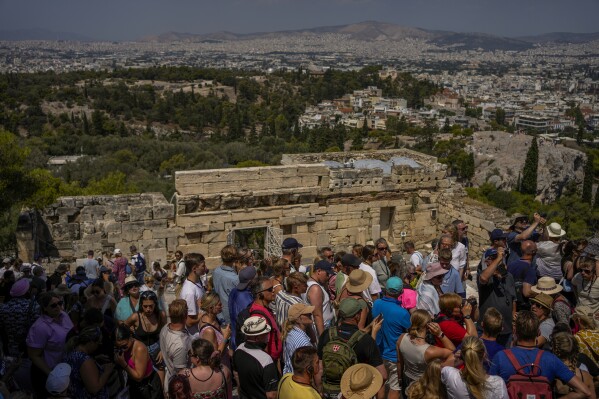 Tourists visit the Acropolis ancient hill, in Athens, Greece, Tuesday, July 4, 2023. Crowds are packing the Colosseum, the Louvre, the Acropolis and other major attractions as tourism exceeds 2019 records in some of Europe’s most popular destinations. While European tourists helped the industry on the road to recovery last year, the upswing this summer is led largely by Americans, who are lifted by a strong dollar and in some cases pandemic savings. (AP Photo/Thanassis Stavrakis)