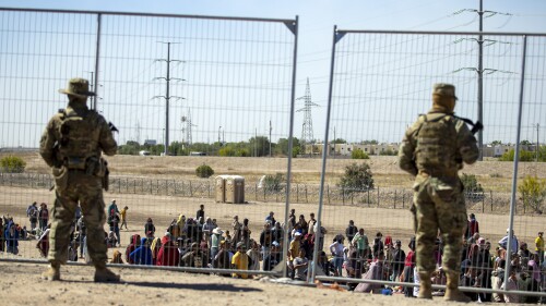 FILE - Migrants wait in line adjacent to the border fence under the watch of the Texas National Guard to enter into El Paso, Texas, May 10, 2023. Border Patrol does not have protocols for assessing medical needs of children with preexisting conditions, according to an independent report made public Tuesday, July 18, on the death of an 8-year-old girl from Panama who was in federal custody. (AP Photo/Andres Leighton, File)