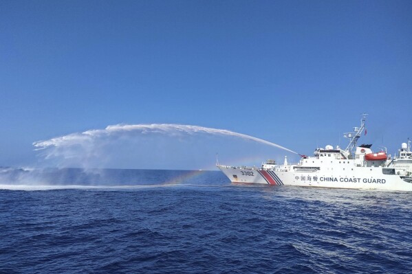 In this photo provided by the Philippine Coast Guard, a Chinese Coast Guard ship, right, uses its water cannons on a Philippine Bureau of Fisheries and Aquatic Resources (BFAR) vessel, not shown, as it approaches Scarborough Shoal in the disputed South China Sea on Saturday Dec. 9, 2023. The Philippines and its treaty ally, the United States, separately condemned a high-seas assault Saturday by the Chinese coast guard and suspected militia ships that repeatedly blasted water cannons to block three Philippine fisheries vessels from a disputed shoal in the South China Sea. (Philippine Coast Guard via AP)