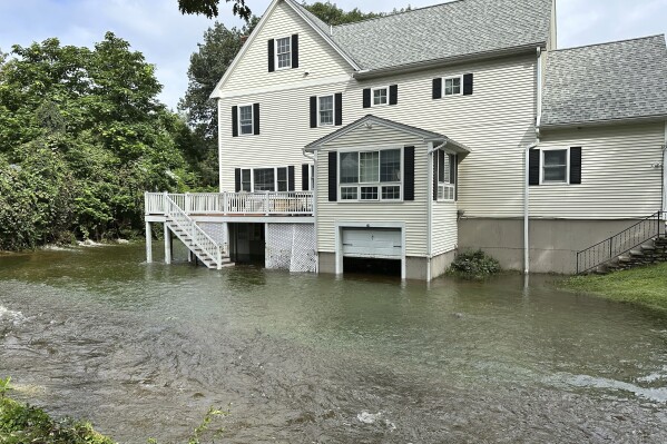 A brook in Leominster, Mass. overflows into the garage of a home following heavy rains overnight, Tuesday, Sept. 12, 2023. (AP Photo/Michael Casey)