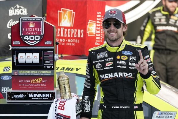 Ryan Blaney stands next to the winner's trophy after the NASCAR Cup Series auto race at Michigan International Speedway, Sunday, Aug. 22, 2021, in Brooklyn, Mich. (AP Photo/Carlos Osorio)