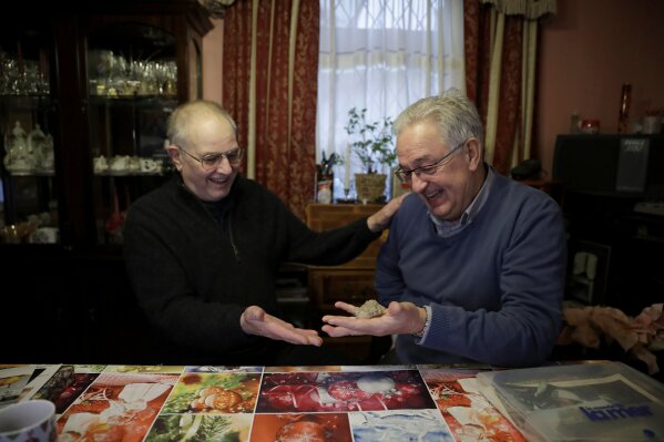 Former British Channel Tunnel worker Graham Fagg, left, gives Former French Channel Tunnel worker Philippe Cozette a piece of water crystal from an adit when he worked on the 1974 Channel Tunnel site, during an interview with The Associated Press at Graham's home in Dover, England, Thursday, Jan. 30, 2020. By digging their way to each other deep under the English Channel, tunnelers Graham Fagg and Philippe Cozette became symbols for British-French friendship when they made the first breakthrough in the Channel Tunnel nearly 30 years ago. (AP Photo/Matt Dunham)