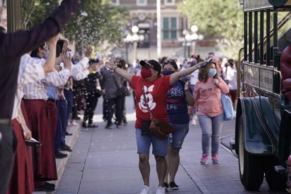 Guests walk down Main Street USA at Disneyland in Anaheim, Calif., Friday, April 30, 2021.  The iconic theme park in Southern California that was closed under the state's strict virus rules swung open its gates Friday and some visitors came in cheering and screaming with happiness.  (AP Photo/Jae Hong)
