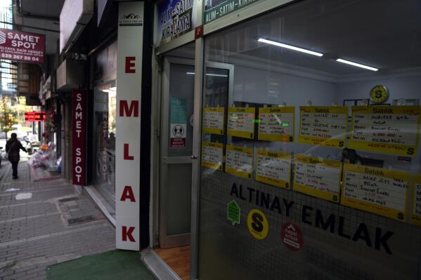 A view of signs advertising apartments for sale and rent displayed on a glass window of a real estate office in Istanbul, Tuesday, Dec. 8, 2022. Economic turmoil driven by inflation of 85% has plunged Turkey into one of its worst property crises. Skyrocketing prices have made finding affordable housing to rent or buy an uphill battle for many, especially for millions earning minimum wage who also struggle to cover food and energy costs. Increasing construction costs and inflation have pushed up housing prices globally. (AP Photo/Khalil Hamra)