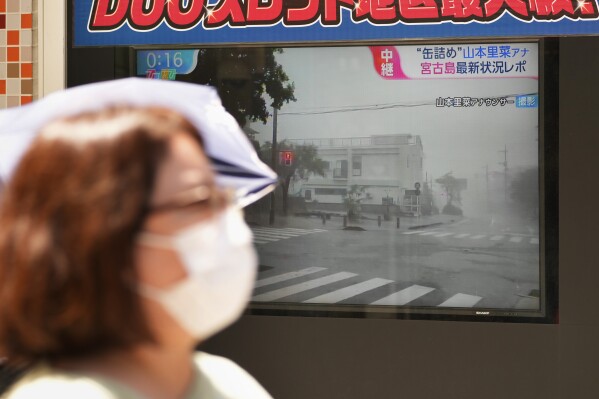 A street TV screen shows news report on the approaching typhoon, in Tokyo, Japan, Friday, Aug. 4, 2023. Residents of Japan's southwestern islands were warned of high winds and rain through the weekend once a nearly stationary Typhoon Khanun starts moving east later Friday. (AP Photo/Shuji Kajiyama)