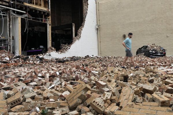 Un hombre camina entre ladrillos que cayeron de un edificio dañado después de que una fuerte tormenta azotara Houston, el viernes 17 de mayo de 2024.  (Foto AP/David J. Phillip)