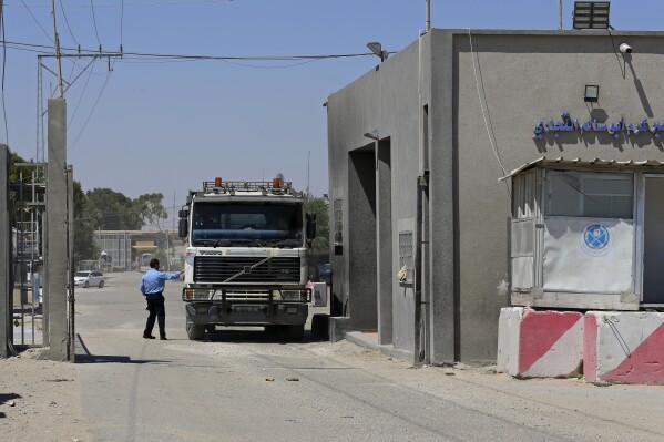 FILE - A Hamas security officer checks a truck entering Gaza at the gate of the Kerem Shalom cargo crossing with Israel, in Rafah, southern Gaza Strip, on June 21, 2021. Israel will reopen the main commercial crossing to Gaza Sunday Sept. 10, 2023, Israeli authorities said, after a nearly weeklong closure that stymied the flow of goods and harmed producers across the embattled territory. (AP Photo/Adel Hana, File)