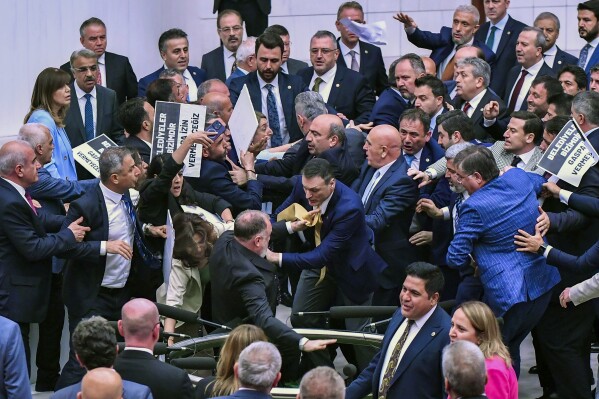 Pro-Kurdish Peoples' Equality and Democracy Party, or DEM, and Justice and Development Party, or AKP, lawmakers scuffle at the parliament in Ankara, Tuesday, June 4, 2024. More than a dozen legislators from Turkey's pro-Kurdish party staged a demonstration in parliament on Tuesday to denounce the arrest and expulsion from office of a newly-elected mayor, Turkish media reported. Boards read in Turkish: 