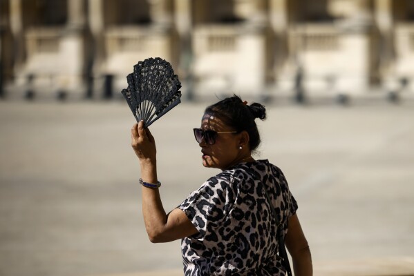 FILE - A woman uses a fan in the courtyard of the Louvre museum, Sept. 7, 2023, in Paris. After a summer of record-smashing heat, warming somehow got even worse in September as Earth set a new mark for how far above normal temperatures were, the European climate agency reported Thursday, Oct. 5. (AP Photo/Thomas Padilla, File)