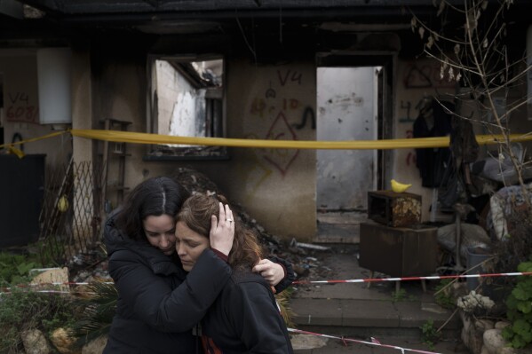 Amit Soussana, 40, right, is embraced by a friend after speaking to journalists in front of her destroyed house in the kibbutz Kfar Azza, near the Gaza Strip, Israel, Monday, Jan. 29, 2024. Soussana was held in captivity for 55 days after being kidnapped during the cross-border attack by Hamas on Oct. 7. (APPhoto/Leo Correa)