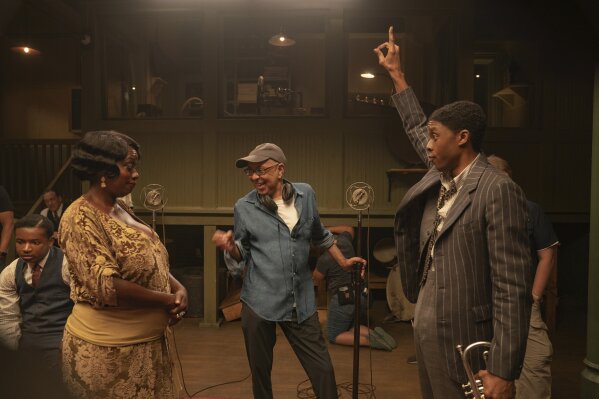 This image released by Netflix shows Viola Davis as Ma Rainey, left, director George C. Wolfe, center, and Chadwick Boseman as Levee during the filming of "Ma Rainey's Black Bottom." Netflix on Monday previewed Wolfe’s August Wilson adaptation showcasing Boseman’s final performance opposite Davis. (David Lee/Netflix via AP)