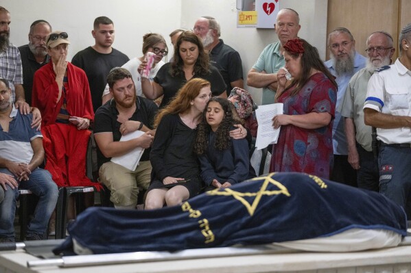 Mourners attend the funeral of Batsheva Nigri, at a cemetery in the West Bank Jewish settlement of Kfar Etzion, Monday, Aug. 21, 2023. Israeli authorities say that a suspected Palestinian attacker has killed an Israeli woman and seriously wounded a man in the incident. (AP Photo/Ohad Zwigenberg)