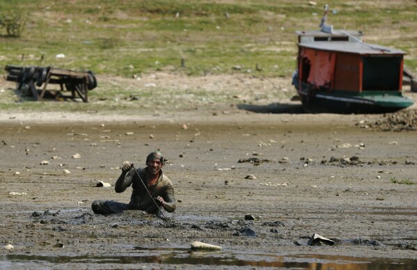 A fisherman searches for eels in the mud of the dried up Paraguay River in Chaco-i, across the river from Asuncion, Paraguay, Thursday, Oct. 8, 2020. The Paraguay River reached its lowest level in 50 years on Friday, Oct. 9, 2020, following months of extreme drought, which has exposed the nation’s economic dependence on the river and limited access to drinking water. (AP Photo/Jorge Saenz)