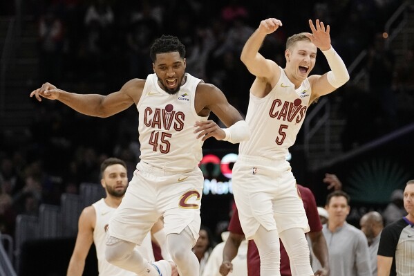 Cleveland Cavaliers guards Donovan Mitchell (45) and Sam Merrill (5) celebrate after a 3-point basket by Merrill in overtime of an NBA basketball game against the Houston Rockets, Monday, Dec. 18, 2023, in Cleveland. (AP Photo/Sue Ogrocki)