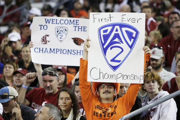 An Oregon State fan, front, and a Washington State fan hold "Pac-2" signs, representing the two schools that will remain in the Pac-12 after the 2023-2024 academic year after the other schools in the conference announced plans to leave, during the second half of an NCAA college football game, Saturday, Sept. 23, 2023, in Pullman, Wash. (AP Photo/Young Kwak)