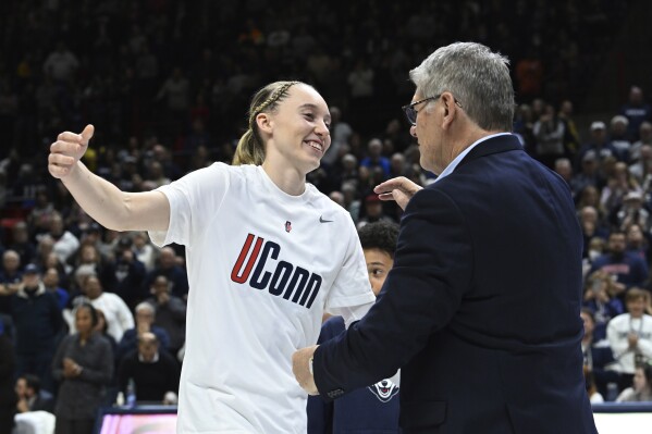 UConn guard Paige Bueckers (5) reaches for coach Geno Auriemma during senior night ceremonies after UConn defeated Georgetown in an NCAA college basketball game Friday, Feb. 16, 2024, in Storrs, Conn. (Cloe Poisson/Hartford Courant via AP)