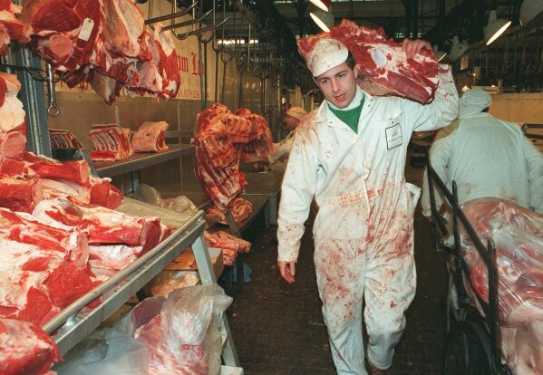 FILE - In this Thursday March 21, 1996 file photo, butcher Graham Poultney carries a leg of beef at London's Smithfield meat market. The European Union banned British beef exports after an outbreak of mad cow disease, prompting one of the biggest fractures in the relationship between Britain and the EU. On Jan. 31, 2020, Britain is scheduled to leave the EU. (AP Photo/Charles Miller, File)