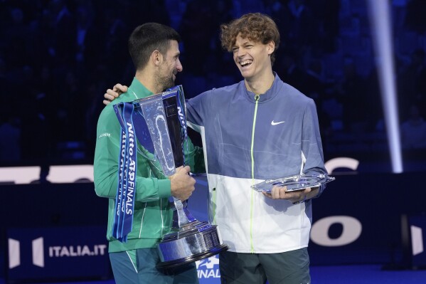 Serbia's Novak Djokovic, winner, left, and second placed Italy's Jannik Sinner hold their trophies at the end of the singles final tennis match of the ATP World Tour Finals at the Pala Alpitour, in Turin, Italy, Sunday, Nov. 19, 2023. (AP Photo/Antonio Calanni)