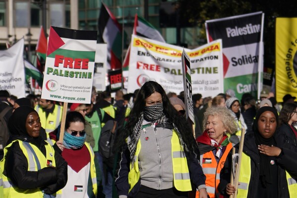 Protesters show placards during a pro-Palestinian protest in London, Saturday, Nov. 11, 2023. London police have stepped up efforts to ensure a pro-Palestinian march on Saturday remains peaceful following a week of political sparring over whether the demonstration should go ahead on the weekend Britain honors its war dead.(AP Photo/Alberto Pezzali)