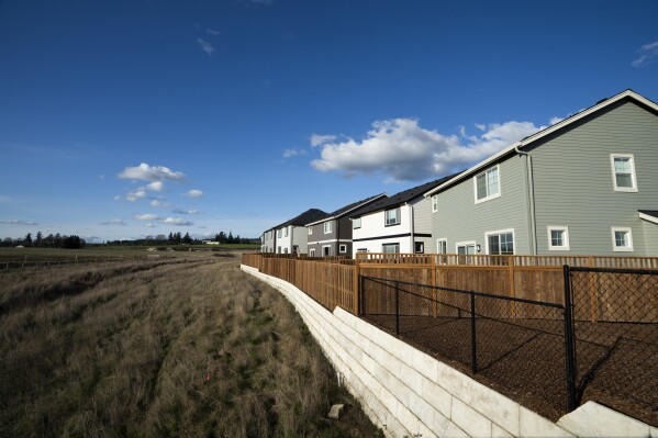 Homes are seen on Thursday, Feb. 22, 2024, in the southwest Portland, Ore., suburb of Beaverton. The so-called urban growth boundary, established by a 1973 law that placed boundaries around cities to prevent urban sprawl and preserve nature and farmland, is seen in the background along SW Tile Flat Road. (AP Photo/Jenny Kane)