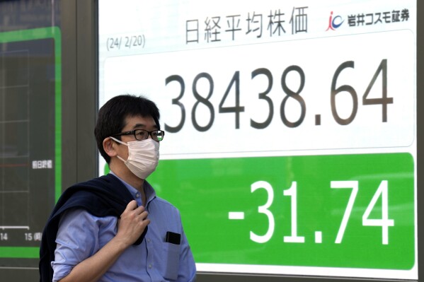 A person walks in front of an electronic stock board showing Japan's Nikkei index at a securities firm Tuesday, Feb. 20, 2024, in Tokyo. Asian shares were trading mixed Tuesday a day after Chinese markets reopened from a long Lunar New Year holiday. (AP Photo/Eugene Hoshiko)