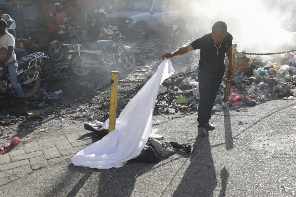 Una persona levanta la sábana que cubría un cadáver en el vecindario Petion Ville de Puerto Príncipe, Haití, el 18 de marzo de 2024. (Foto AP/Odelyn Joseph)