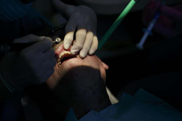 FILE - A dentist works on polishing and contouring the teeth of a patient at his dental office in Virginia Beach. Va. For millions of low-income New Yorkers, access to routine dental care has long hinged on whether or not they have eight crucial teeth. Under a new legal settlement reached Monday, May 1, 2023, the New York Department of Health must lift some of its most restrictive rules for Medicaid recipients, including the long-standing "eight points of contact" policy. The change will expand dental coverage for an estimated 5 million people. (Kristen Zeis/The Virginian-Pilot via AP, File)