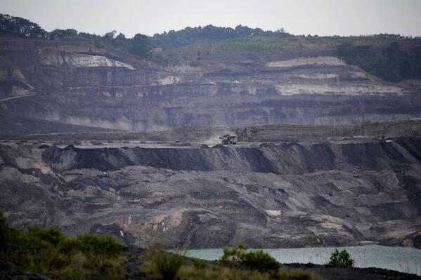 A dump truck carrying coal navigates its way near a coal mining pit in Sanga-Sanga, East Kalimantan, Indonesia, Tuesday, Dec. 20, 2022. Indonesia, one of the world's largest coal-producing countries, has agreed to drastically reduce its reliance on fossil fuels in the coming decades. (AP Photo/Dita Alangkara)