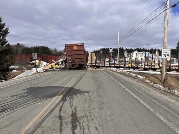 A photo released by the Maine Department of Public Safety shows a train derailment on Route 11, Wednesday, April 3, 2024, in Masardis, northern Maine. Maine officials on Thursday are investigating why a tractor-trailer crashed into a freight train, causing two cars to derail and injuring the truck's driver and his dog. (The Maine Department of Public Safety via AP)
