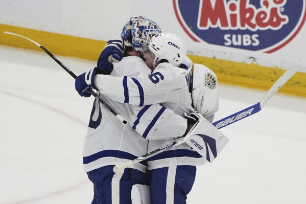 Toronto Maple Leafs goaltender Joseph Woll, left, is hugged by right wing Mitch Marner (16) after the Maple Leafs defeated the Florida Panthers in Game 6 of a second-round NHL hockey playoff series, Friday, May 16, 2025, in Sunrise, Fla. (AP Photo/Lynne Sladky)