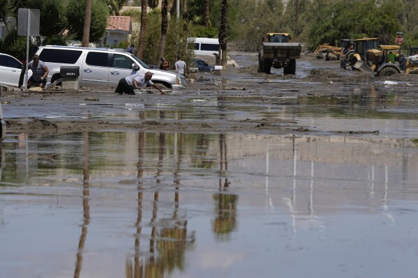 People try to clean up after the street was flooded with mud Monday, Aug. 21, 2023, in Cathedral City, Calif. Forecasters said Tropical Storm Hilary was the first tropical storm to hit Southern California in 84 years, bringing the potential for flash floods, mudslides, isolated tornadoes, high winds and power outages. (AP Photo/Mark J. Terrill)