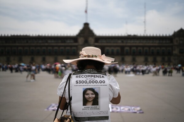 FILE - Maria Hochihuat Pérez, whose daughter Nimbe disappeared five years ago, holds a sign offering a cash reward during a national march to find her mother, in Mexico City, May 10, 2024. The march came two days after President Lopez Obrador's administration accused media outlets and volunteer searchers looking for the remains of missing people of 