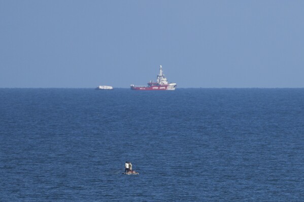 A ship belonging to the Open Arms aid group approaches the shores of Gaza towing a barge with 200 tons of humanitarian aid on Friday, March 15, 2024. (AP Photo/Abdel Kareem Hana)