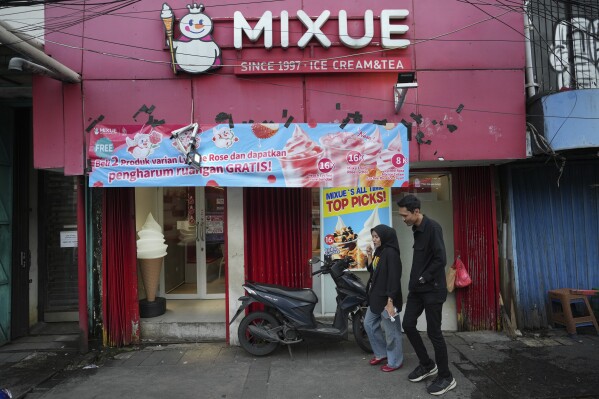 People walk past a Mixue store in Jakarta, Indonesia, Wednesday, Feb. 19, 2025. (AP Photo/Achmad Ibrahim)