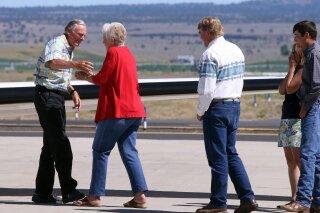 FILE - In this July 11, 2018, file photo, rancher Dwight Hammond Jr., left, is embraced by his wife, Susie Hammond, after arriving by private jet at the Burns Municipal Airport in Burns, Ore. Hammond and his son Steven, convicted of intentionally setting fires on public land in Oregon, were pardoned by President Donald Trump. The U.S. Bureau of Land Management in the final days of the Trump administration issued a grazing permit to Oregon ranchers whose imprisonment sparked the 2016 armed takeover of a federal wildlife refuge by right-wing extremists. (Beth Nakamura/The Oregonian via AP, File)