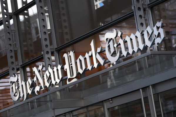 A sign for The New York Times hangs above the entrance to its building, May 6, 2021, in New York. (AP Photo/Mark Lennihan, File)