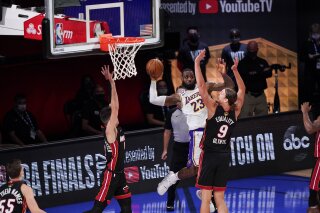 Los Angeles Lakers' LeBron James (23) passes the ball against Miami Heat's Kelly Olynyk (9) and Miami Heat's Tyler Herro (14) during the second half in Game 3 of basketball's NBA Finals, Sunday, Oct. 4, 2020, in Lake Buena Vista, Fla. (AP Photo/Mark J. Terrill)