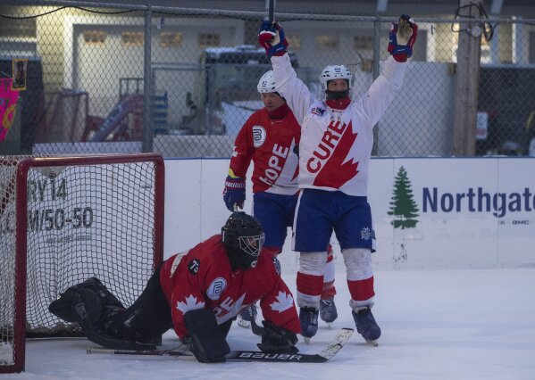 Goalie Andrew Buchanan is scored on as Justin Christopher celebrates during the World's Longest Hockey Game near Edmonton on Thursday, Feb. 11, 2021.   Forty players are taking part in the game that will last 252 hours, to raise money for cancer research.  (Jason Franson/The Canadian Press via AP)