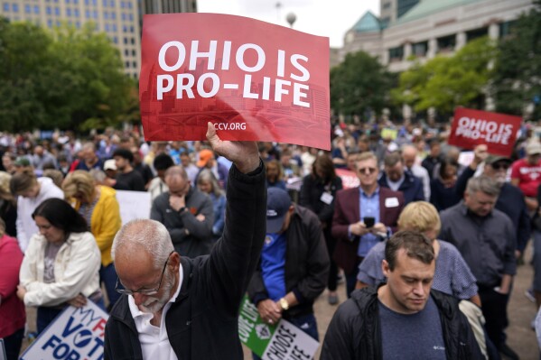 FILE - Paul Meacham holds high a sign that reads "Ohio is pro-life" as the crowd prays during the Ohio March for Life rally at the Ohio State House in Columbus, Ohio, Friday, Oct. 6, 2023. Two years after the U.S. Supreme Court ended a nationwide right to abortion, travel and pills have become big parts of the issue. (AP Photo/Carolyn Kaster, File)