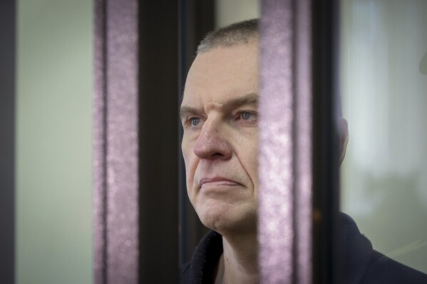 FILE - Journalist Andrzej Poczobut stands in a defendants' cage during a court session in Grodno, Belarus, on Jan. 16, 2023. A representative of the Polish community in Belarus says a former correspondent for a top Polish newspaper has been denied life-saving heart medication in a Belarusian prison. Andrzej Poczobut has been placed in solitary confinement with no access to lawyers or medical care, according to the Union of Poles in Belarus. (Leonid Shcheglov/Pool via AP, File)
