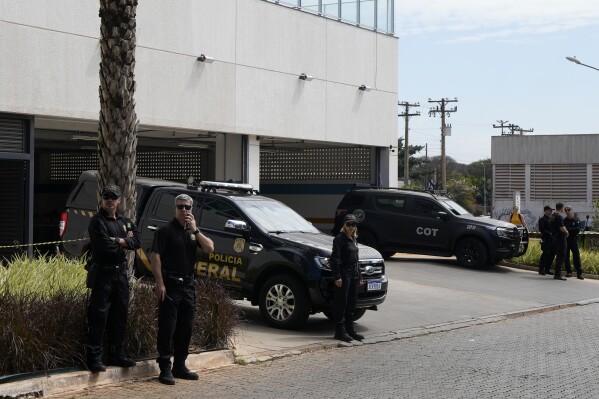 Federal Police agents stand at Federal Police headquarters minutes before the arrival of Brazil's former President Jair Bolsonaro who will testify in Brasilia, Brazil, Thursday, Aug. 31, 2023. Bolsonaro and seven others were summoned to answer questions about the sale of luxury goods reportedly worth millions, that the former leader received as gifts from Saudi Arabia while in office, according to a Brasilia federal police officer who spoke on condition of anonymity to discuss the ongoing investigation. (AP Photo/Eraldo Peres)