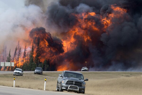 FILE - A wildfire burns south of Fort McMurray, Alberta, near Highway 63 on Saturday, May 7, 2016. A book about an inferno that ravaged a Canadian city and has been called a portent of climate chaos has won Britain’s leading nonfiction book prize. John Valliant’s “Fire Weather: A True Story from a Hotter World” was awarded the 50,000 pound ($62,000) Baillie Gifford Prize at a ceremony in London on Thursday, Nov. 16, 2023. (Jonathan Hayward /The Canadian Press via AP, File)