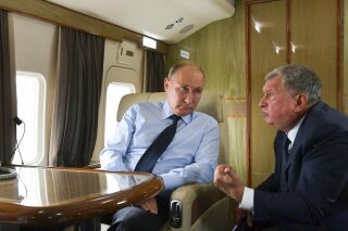 FILE - In this Aug. 27, 2018 file photo, Russian President Vladimir Putin, left, listens to Russian Rosneft CEO Igor Sechin during his flight to visit Chernigovets coal mine, in Beryozovsky, Kemerovo region, Russia. On Tuesday, Feb. 18, 2020, the Treasury Department slapped sanctions on Rosneft’s trading arm and its CEO, accusing the Geneva-based firm of providing a critical lifeline to Venezuela’s President Nicolas Maduro. (Alexei Druzhinin, Sputnik, Kremlin Pool Photo via AP, File)