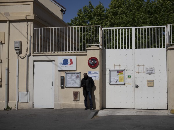 A man stands outside of the La Cabucelle school, a public in elementary school in Marseille, southern France, Monday, April 22, 2024. (AP Photo/Daniel Cole)