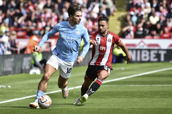 Manchester City's Jack Grealish, left, challenges for the ball with Sheffield United's George Baldock during the English Premier League soccer match between Sheffield United and Manchester City at Bramall Lane in Sheffield, England, Sunday, Aug. 27, 2023. (AP Photo/Rui Vieira)