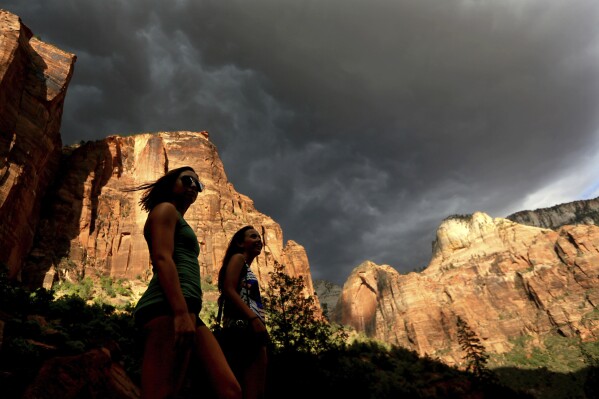 Hikers look up at a fast moving storm as it makes its way through Zion National Park outside of Springdale, Utah, July 22, 2013. (AP Photo/Sandy Huffaker, File)