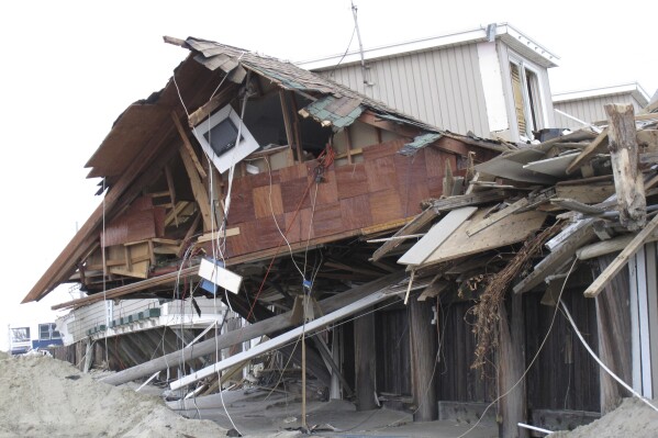 An oceanfront beach club in Sea Bright, N.J., is in ruins on Nov. 15, 2012, two weeks after Superstorm Sandy devastated the town. New Jersey, like places around the world, is setting ambitious goals to deal with climate change, but it wrestling with how much to actually require of businesses and individuals to fulfill those goals. (AP Photo/Wayne Parry)