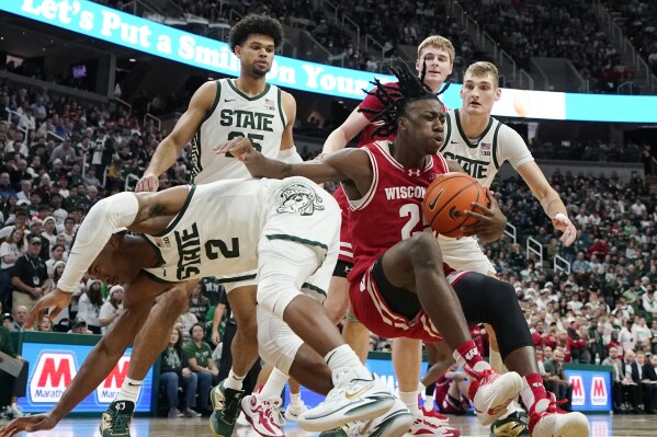 Wisconsin guard AJ Storr (2) falls with the rebound next to Michigan State guard Tyson Walker (2) during the first half of an NCAA college basketball game, Tuesday, Dec. 5, 2023, in East Lansing, Mich. (AP Photo/Carlos Osorio)