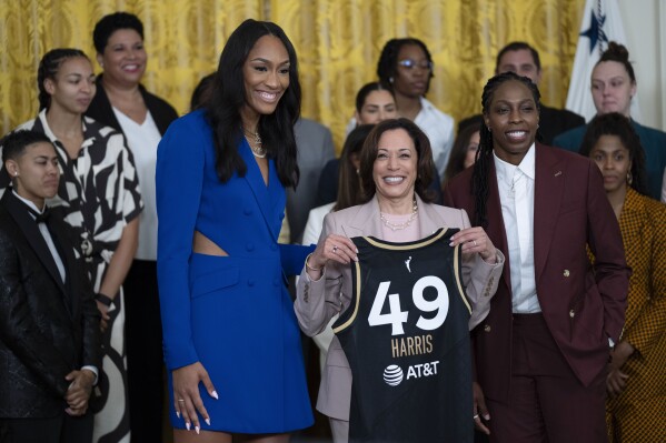 Vice President Kamala Harris is presented with a Las Vegas Aces jersey by Aces' A'ja Wilson, left, and Chelsea Gray, right, during a ceremony welcoming the Las Vegas Aces to the White House to celebrate their 2022 WNBA Championship in the East Room, Friday, Aug. 25, 2023, in Washington. (AP Photo/Manuel Balce Ceneta)